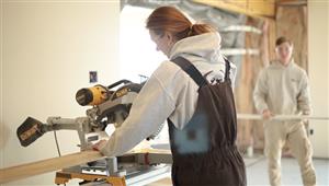 Female Construction student uses cross-cut saw to prepare a stud 